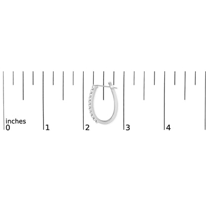 Close-up of one white metal earring with channel-set white baguette-shaped gemstones placed next to a ruler for size reference.