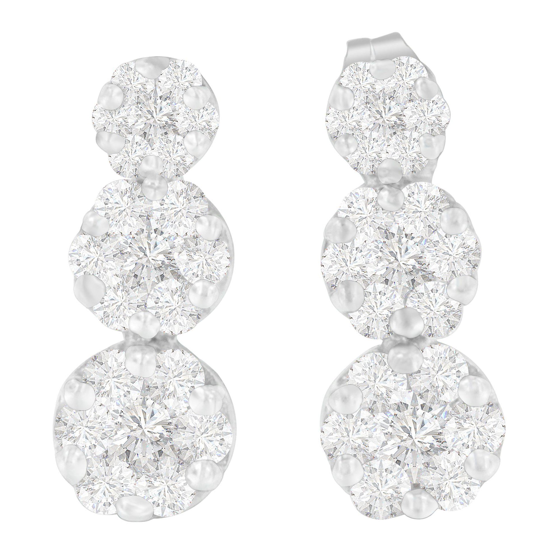 Pair of white metal earrings with three clusters of round white gemstones in prong settings, shown from a front angle.