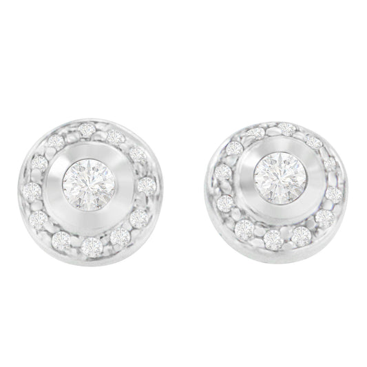 Front view of a pair of white metal round stud earrings, each featuring a central round gemstone in bezel setting surrounded by a circle of smaller round gemstones in prong settings.