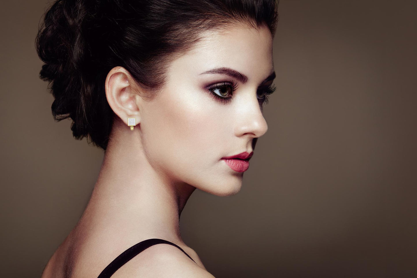 Side view of a model wearing square-shaped yellow metal earrings with multiple small white gemstones in an invisible setting.
