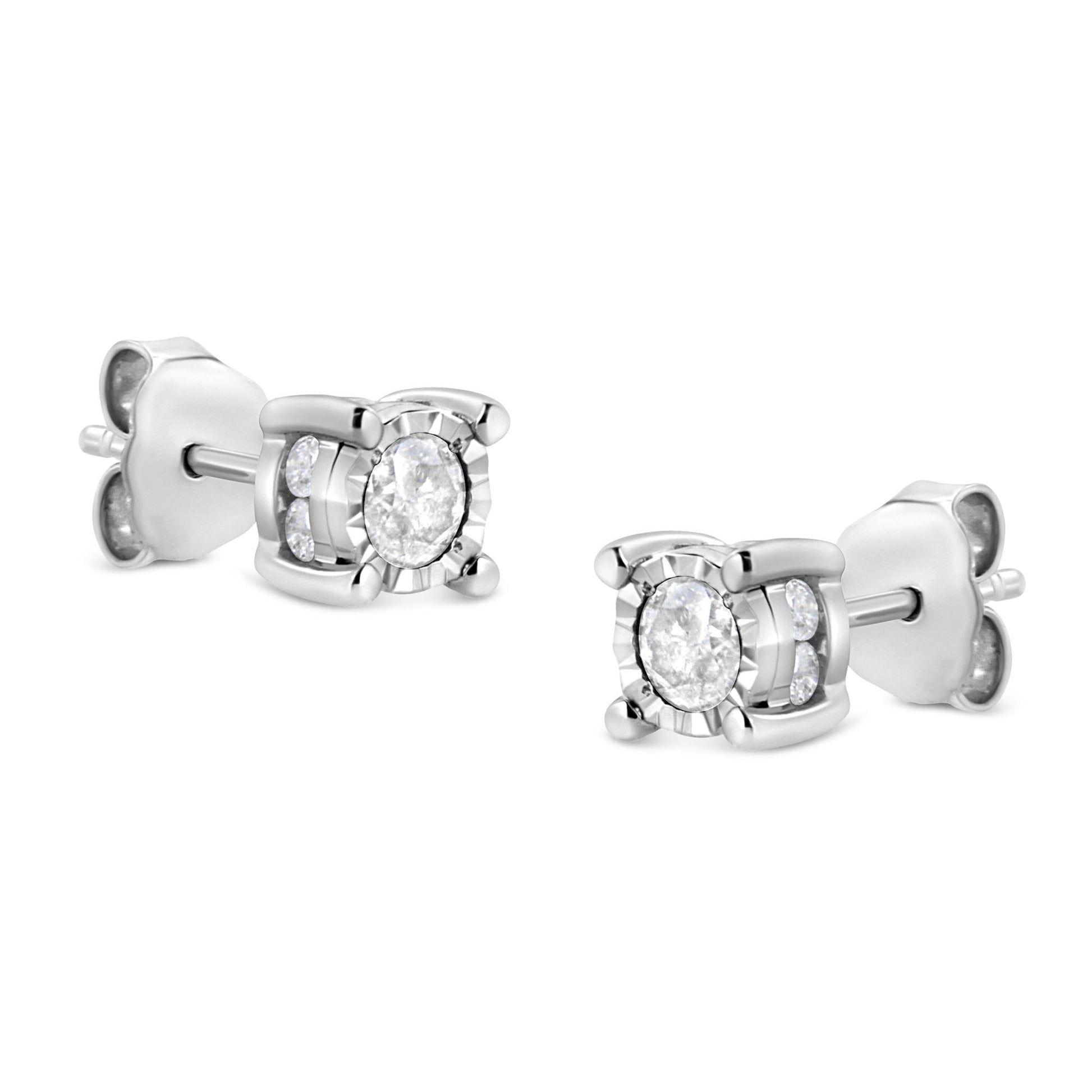 Pair of white metal stud earrings with round white gemstones in miracle and channel settings, shown at a slight angle.