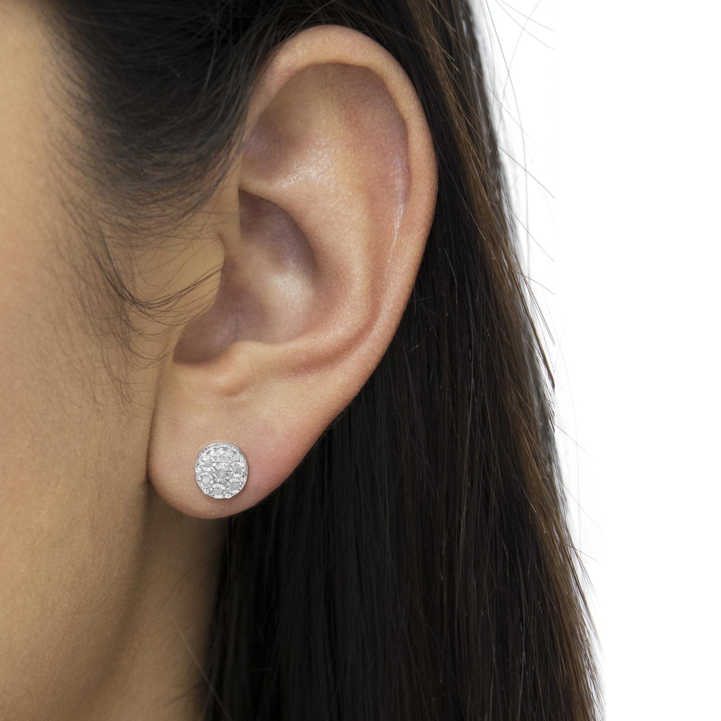 Close-up side view of a white metal round stud earring with multiple small white gemstones in miracle setting, worn on a model's ear.