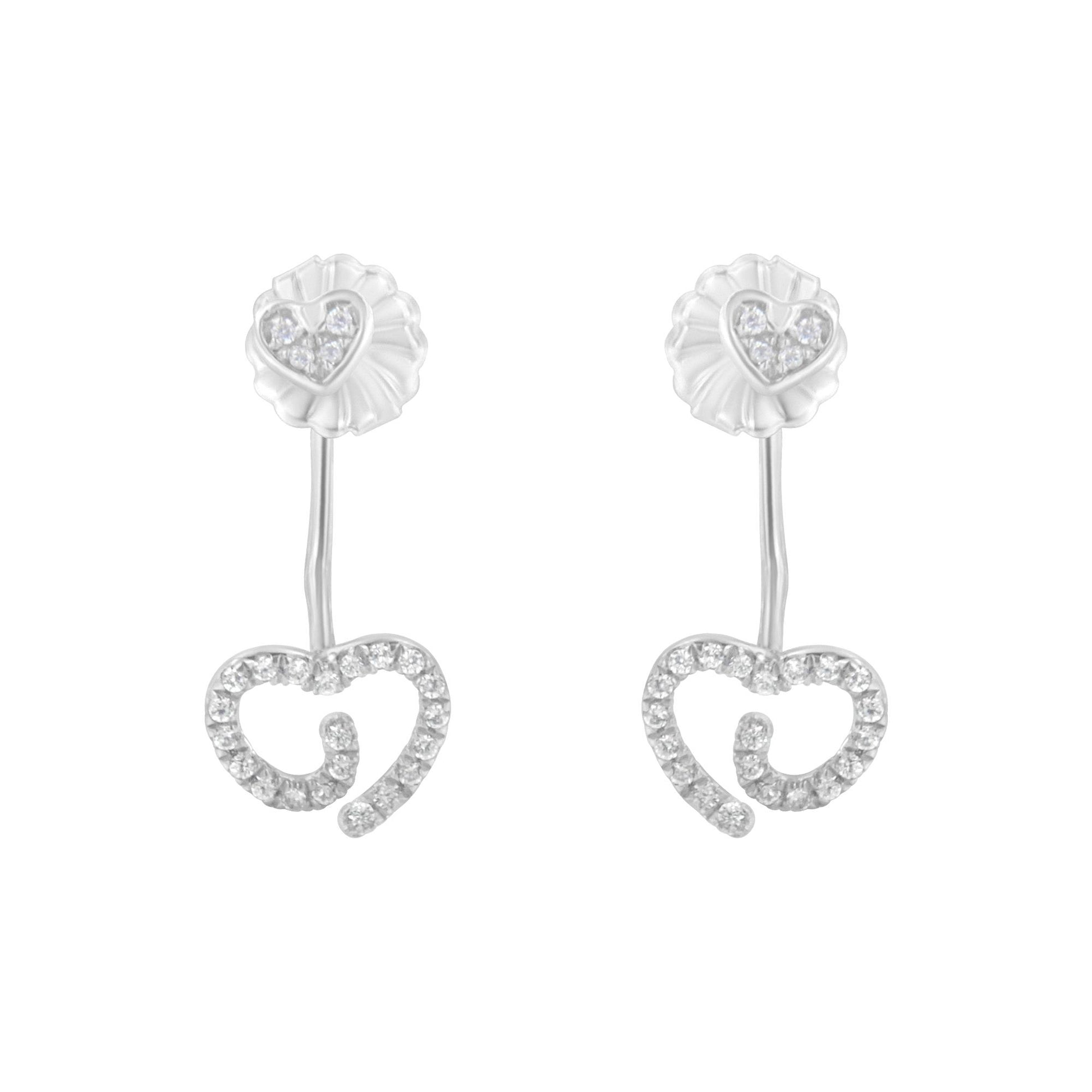 Front view of white metal earrings featuring a small heart with white gemstones at the top connected by a slender bar to a larger open heart shape outlined with white gemstones.