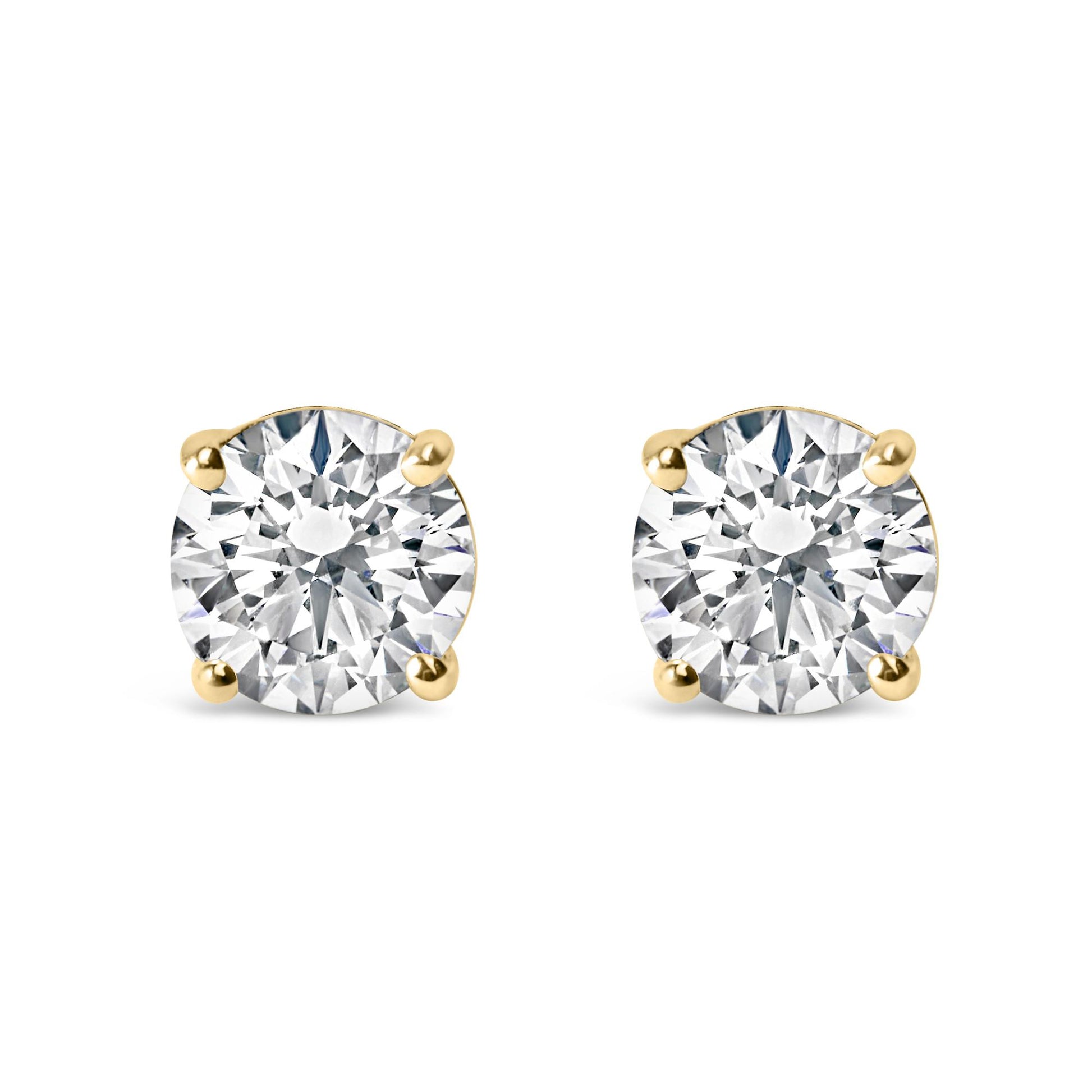 Front view of yellow metal stud earrings each featuring a round white gemstone in a four-prong setting.
