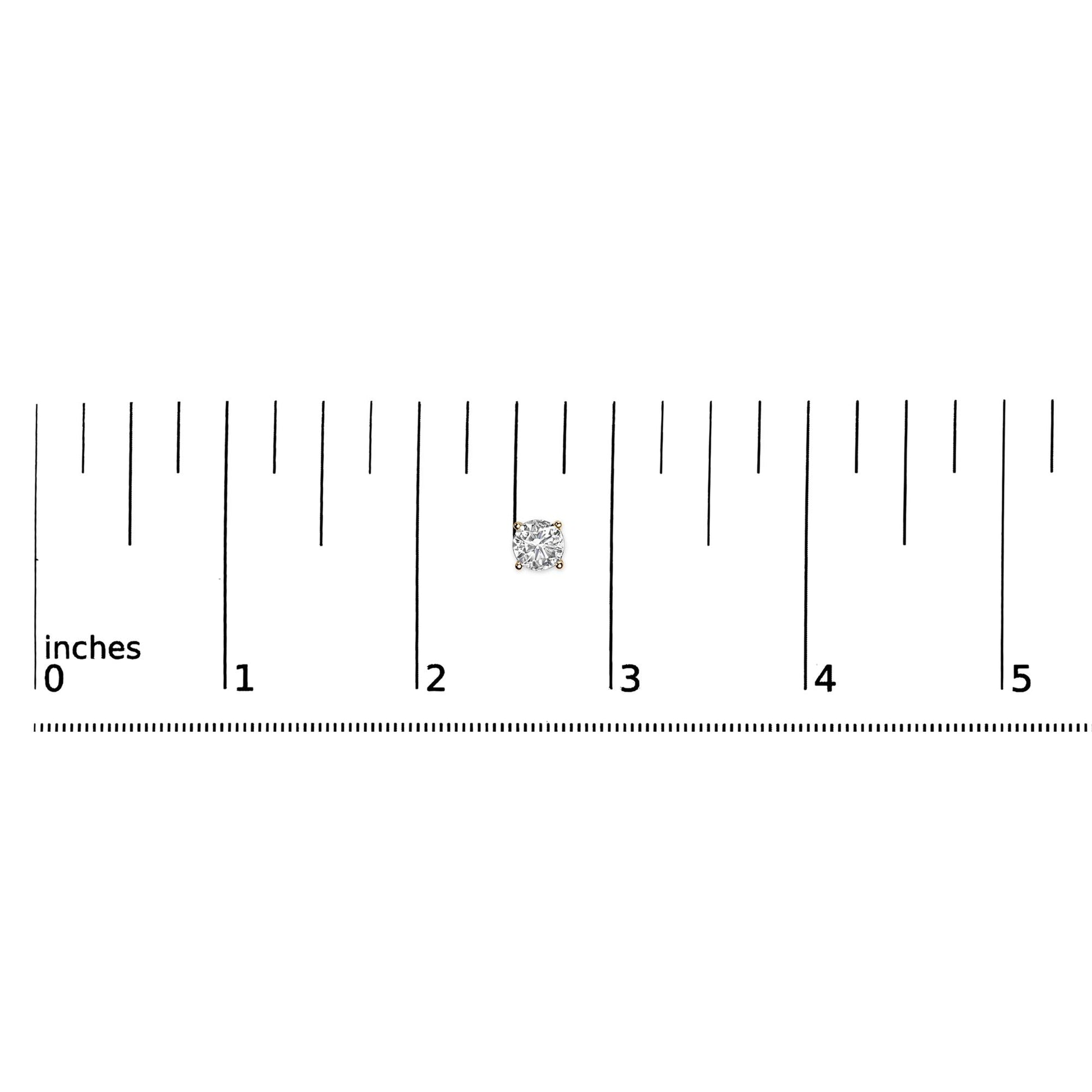 Close-up top view of a single yellow metal stud earring with a round white gemstone in a 4-prong setting placed on a ruler for size reference.