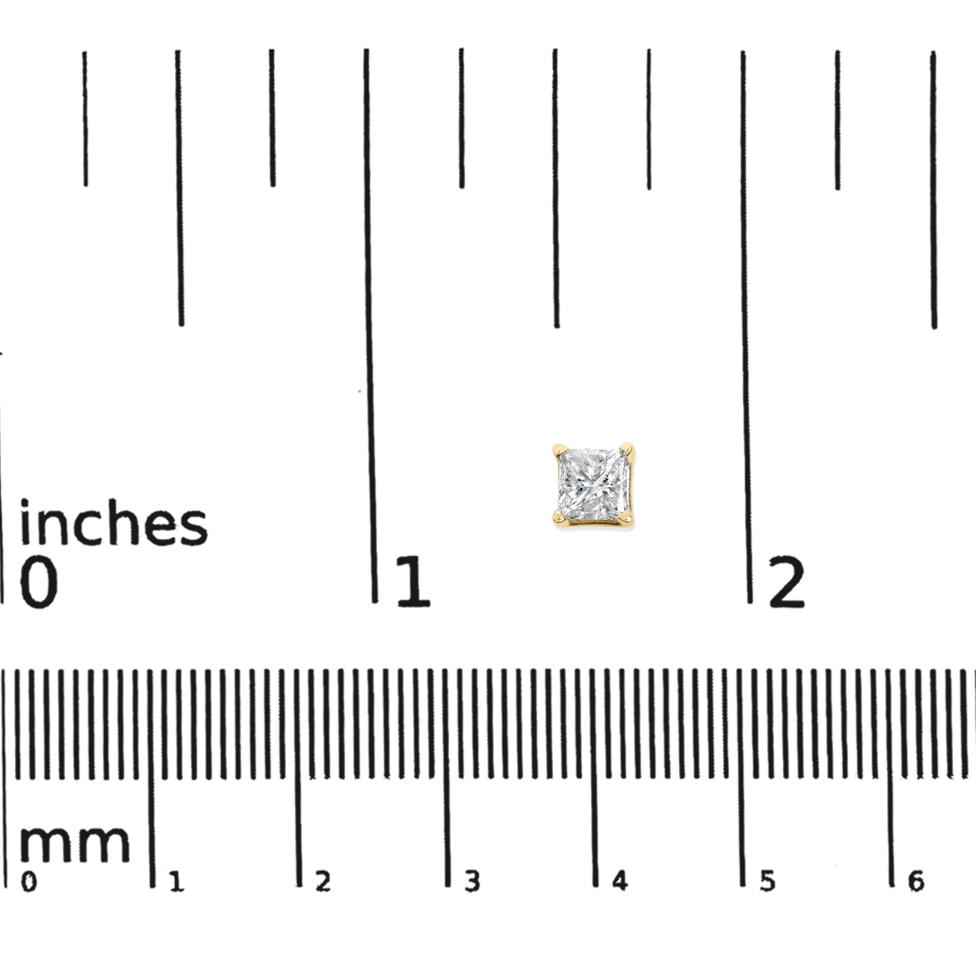 Single yellow metal earring with princess shape white gemstone in 4-prong setting, shown on a ruler for size reference, top-down view.