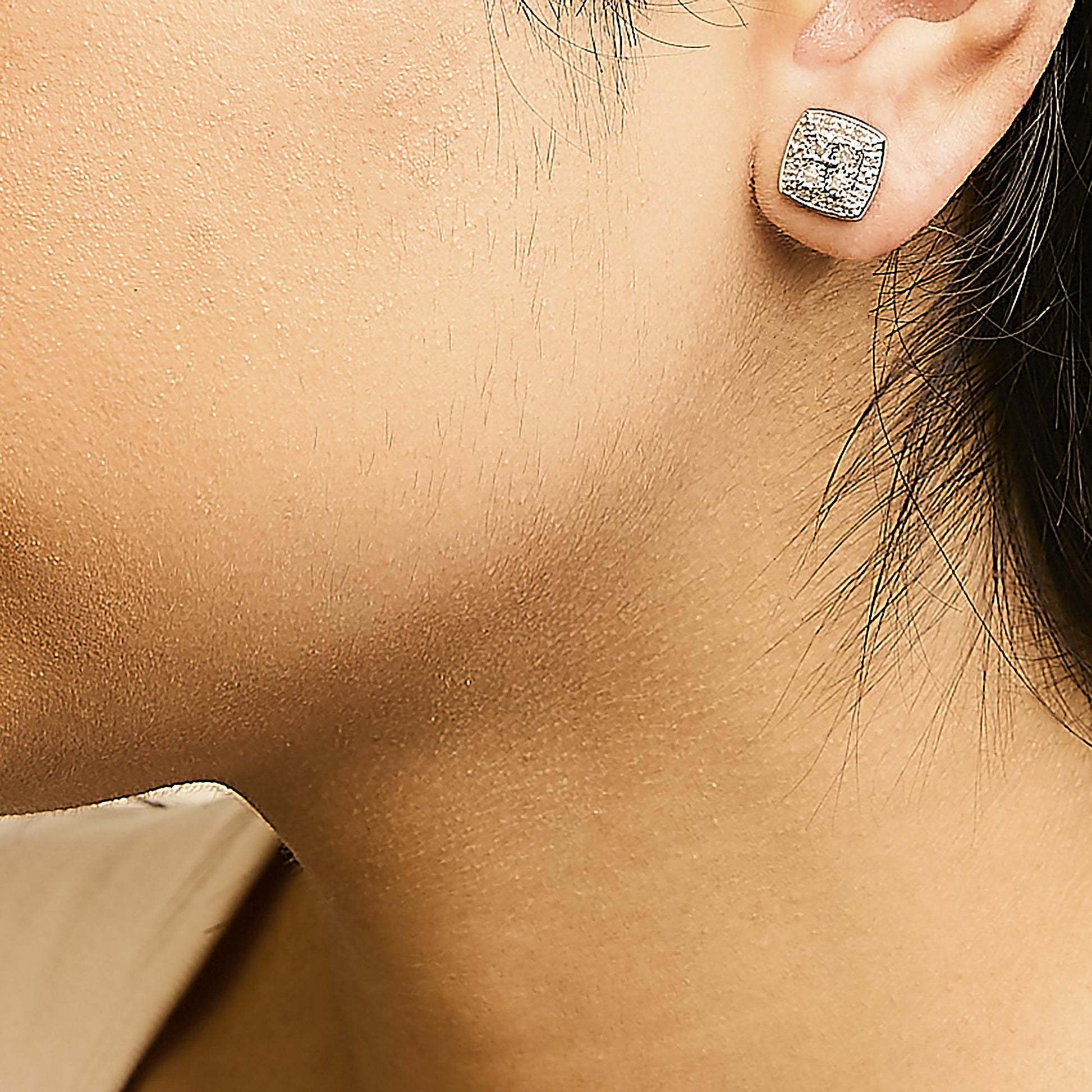 Close-up side view of a model wearing a square-shaped white metal stud earring featuring multiple round white gemstones in a miracle setting.