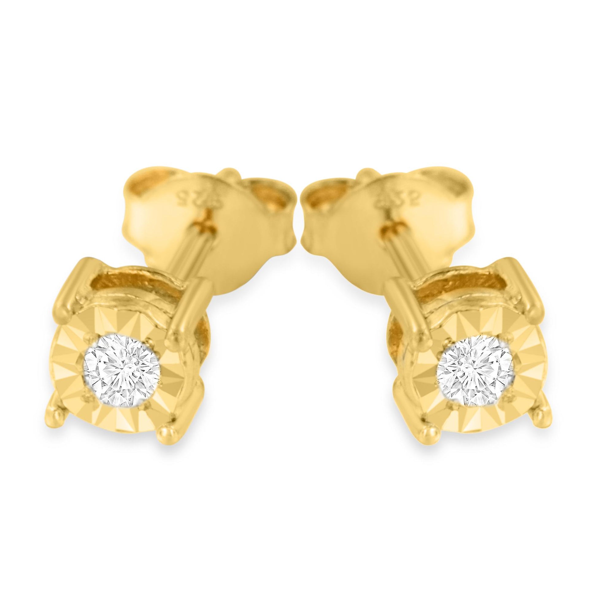 Close-up front angle of a pair of yellow metal stud earrings each featuring a single round white gemstone in a miracle setting.