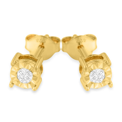 Close-up front angle of a pair of yellow metal stud earrings each featuring a single round white gemstone in a miracle setting.