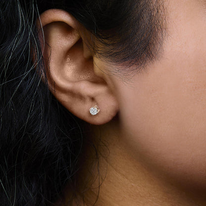 Close-up side view of a rose-colored stud earring with a round white gemstone in miracle setting, worn on a model's ear.