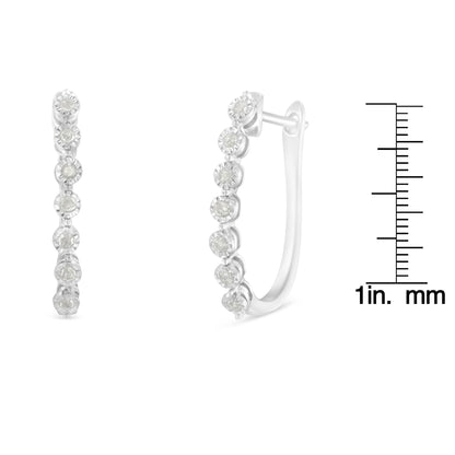 Front and side view of white metal hoop earrings with round white gemstones in miracle setting, shown next to a ruler for size reference.