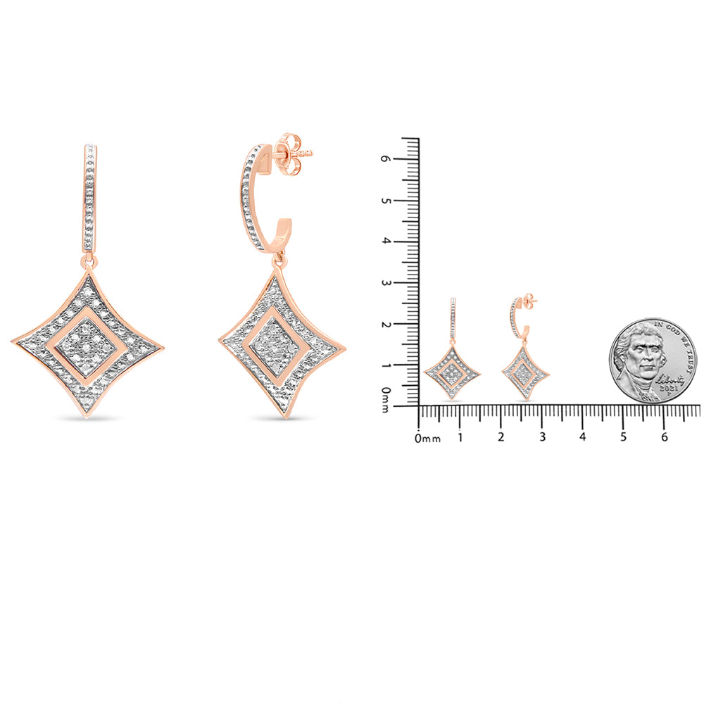 Pair of rose metal earrings with diamond-shaped dangles featuring pave set white round gemstones, shown from front and side angles, displayed on a scale for size reference.