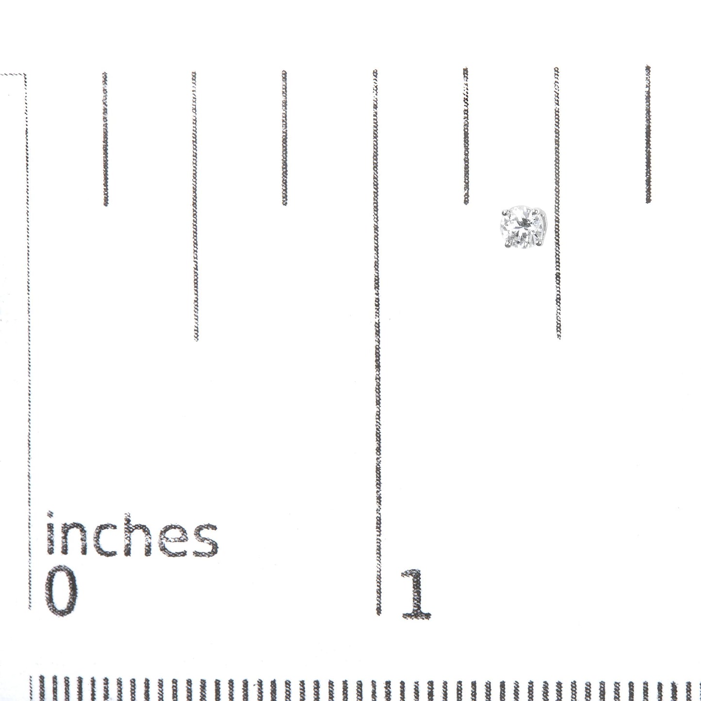 White metal stud earring with round white gemstones in 4-prong settings, displayed on a ruler for size reference, top view.