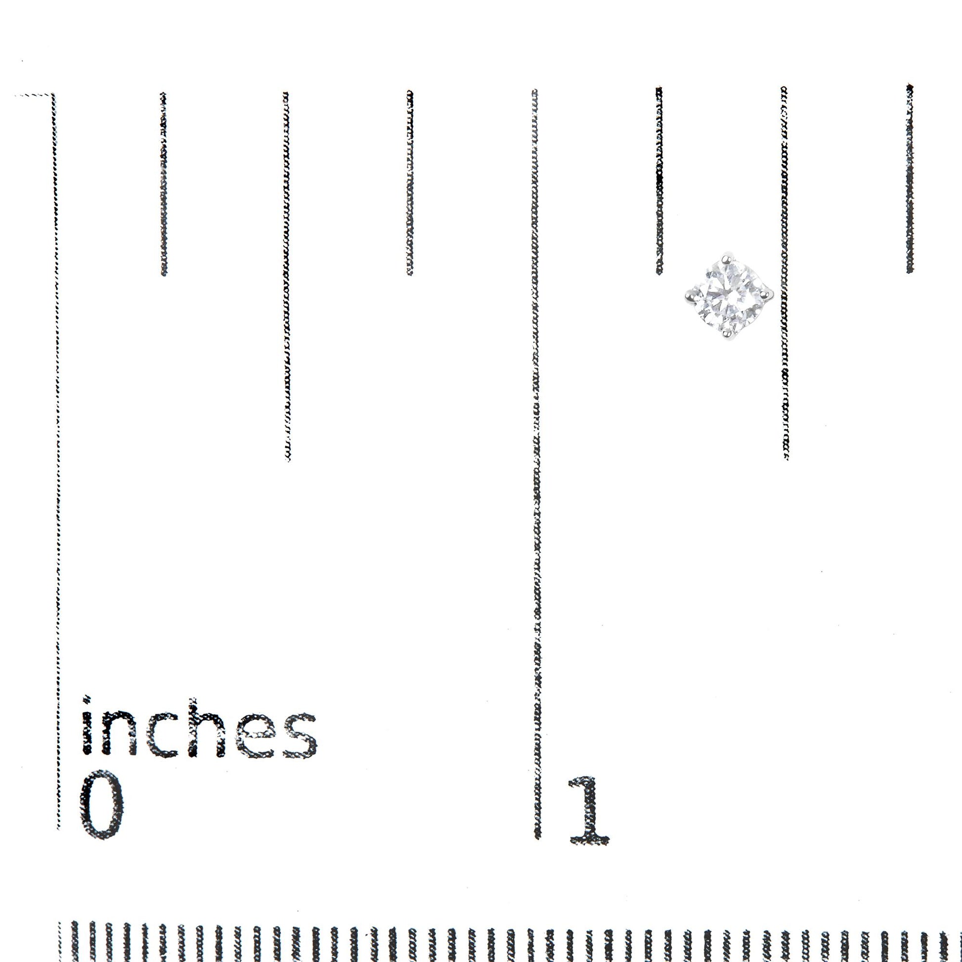 Close-up front angle of a white metal stud earring with a round white gemstone in a four-prong setting placed on a ruler for size reference.