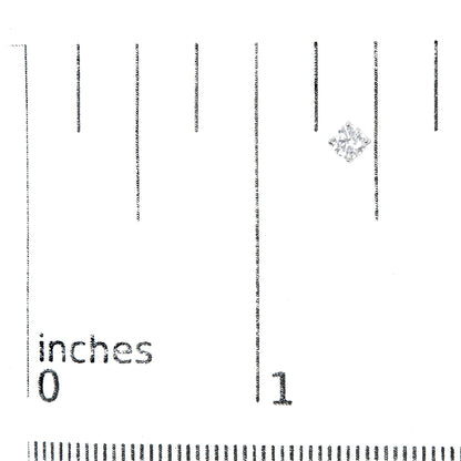 Close-up front angle of a white metal stud earring with a round white gemstone in a four-prong setting placed on a ruler for size reference.