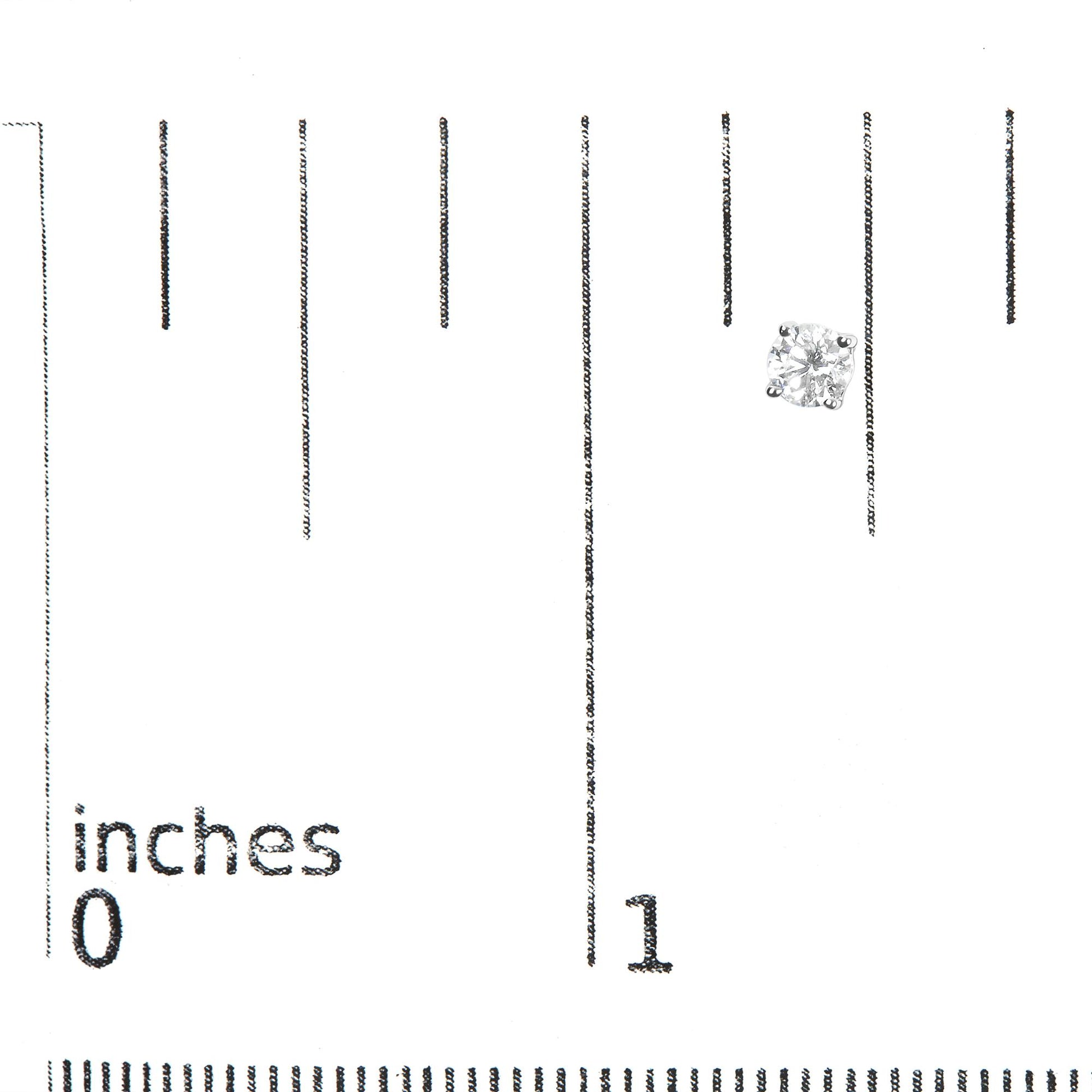 Close-up front angle of a single white metal stud earring with a round white gemstone in a four-prong setting on a ruler for size reference.