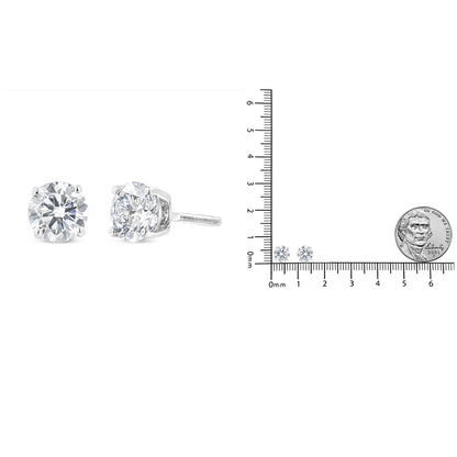 White metal stud earrings with round white gemstones in 4-prong settings, shown in a close-up side and front angle, placed next to a ruler and coin for size reference.