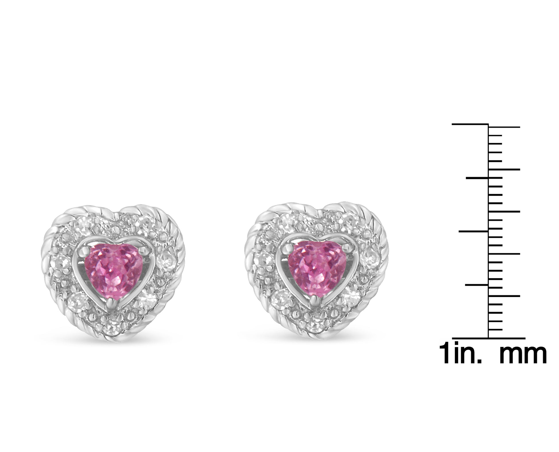 Front view of white metal heart-shaped earrings with pink heart-shaped gemstones surrounded by round white gemstones, shown on a ruler for size reference.