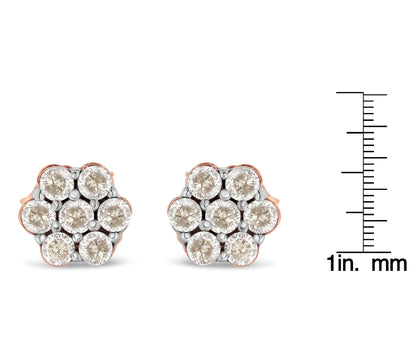 Front view of rose-colored metal stud earrings with clustered round white gemstones, shown next to a ruler for size reference.