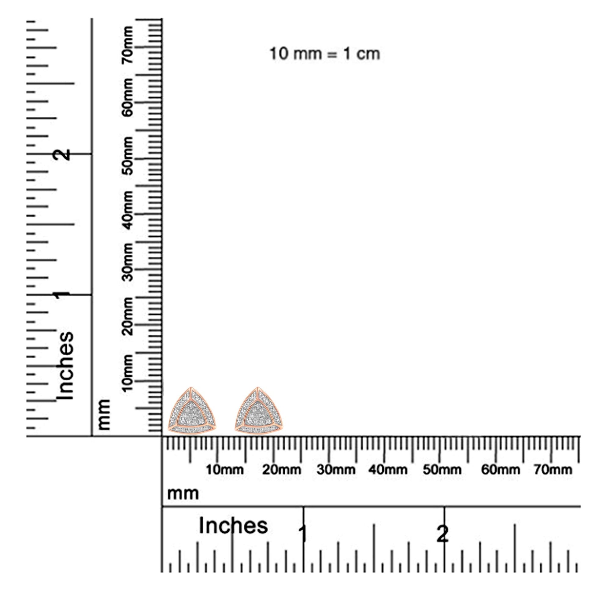 Close-up front view of rose metal triangular earrings with pave-set white round gemstones, displayed on a ruler for size reference.