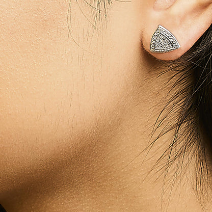 Close-up side view of a triangular white metal earring with a pave setting of round white gemstones, worn on a model.