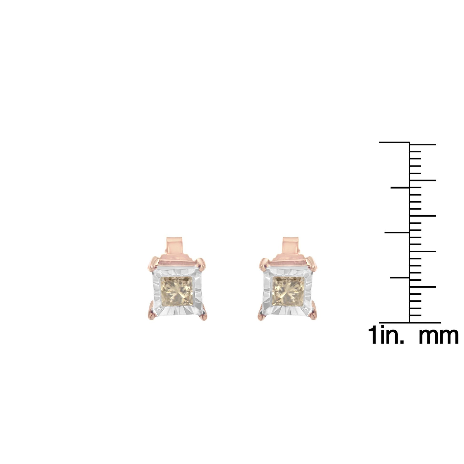 Front view of white and rose colored metal earrings with square brownish gemstones, shown next to a ruler for size reference.