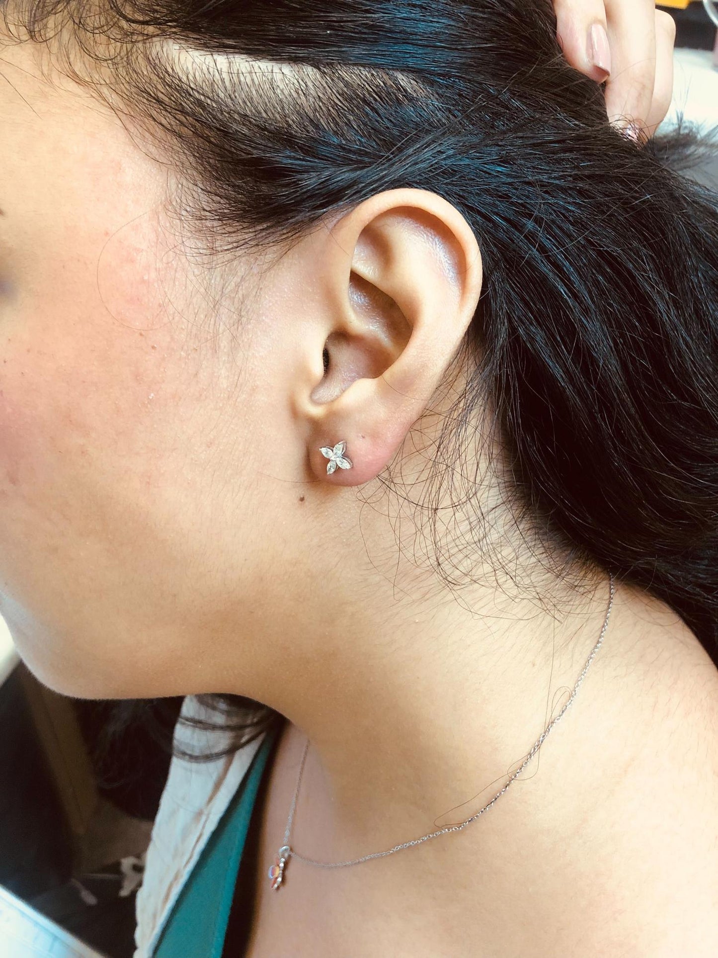White metal earrings shown worn on a model, featuring a cluster of marquise-shaped white gemstones arranged in a floral pattern, viewed from the side.