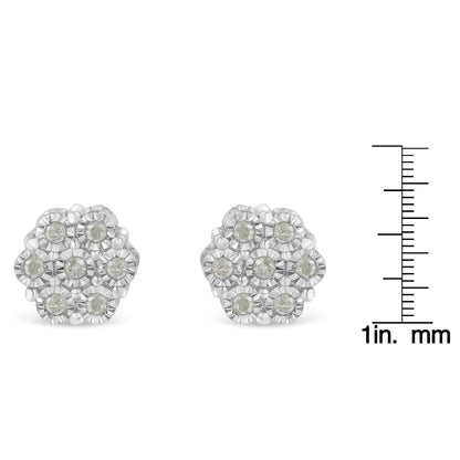 Front view of white metal flower-shaped earrings with round white gemstones, shown next to a ruler for size reference.