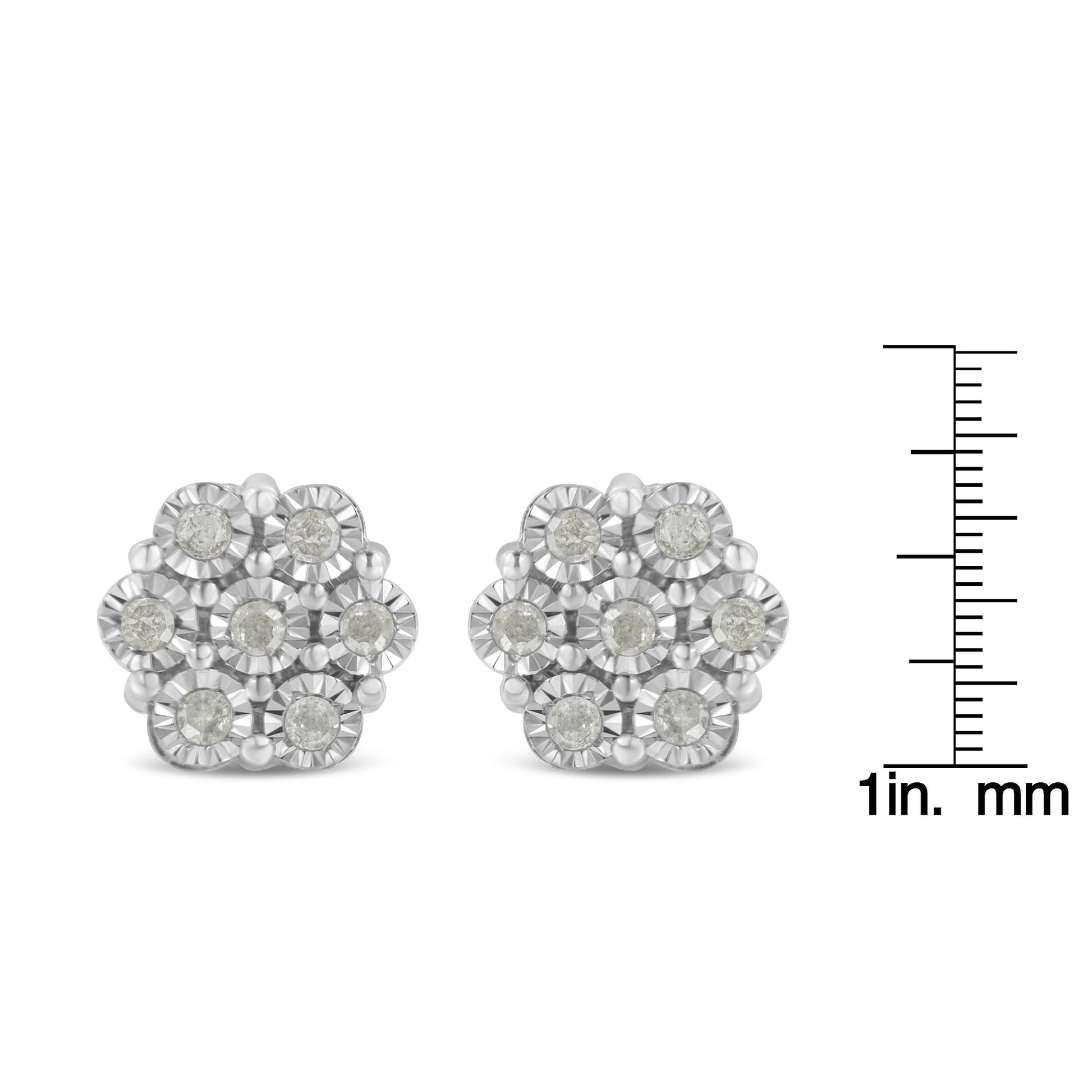 Front view of white metal cluster earrings with round white gemstones in a miracle setting, displayed next to a ruler for size reference.