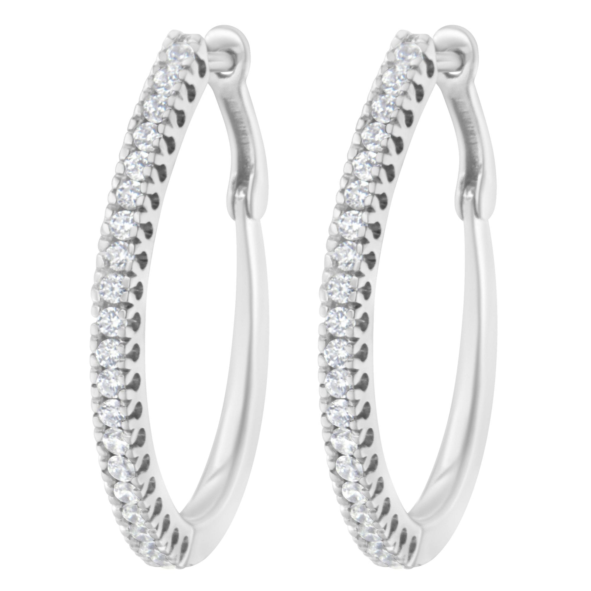 Close-up front view of a pair of white metal hoop earrings set with multiple round white gemstones in a prong setting along the front outer edge.