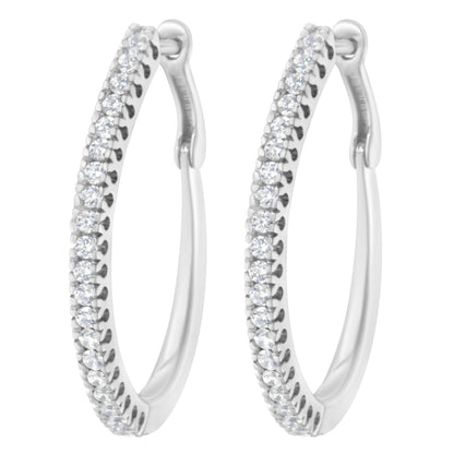 Close-up front view of a pair of white metal hoop earrings set with multiple round white gemstones in a prong setting along the front outer edge.