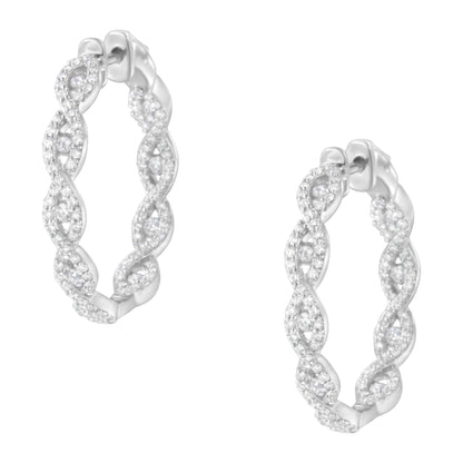 Pair of white metal hoop earrings with an intertwined design, set with multiple round white gemstones, shown at a slight angle.