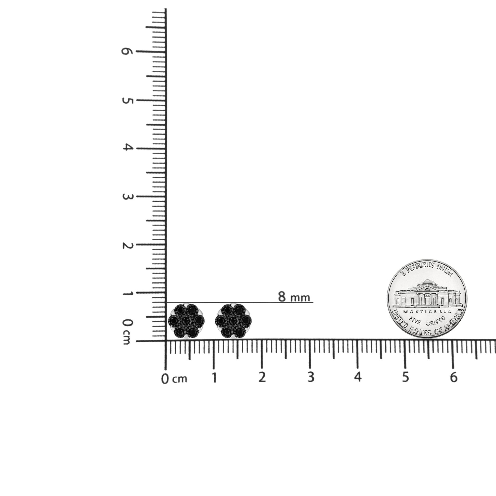Pair of white metal earrings with round black gemstones arranged in a floral cluster design, shown from the front on a ruler for size reference.