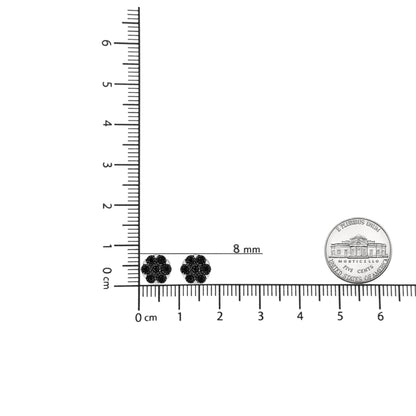 Pair of white metal earrings with round black gemstones arranged in a floral cluster design, shown from the front on a ruler for size reference.