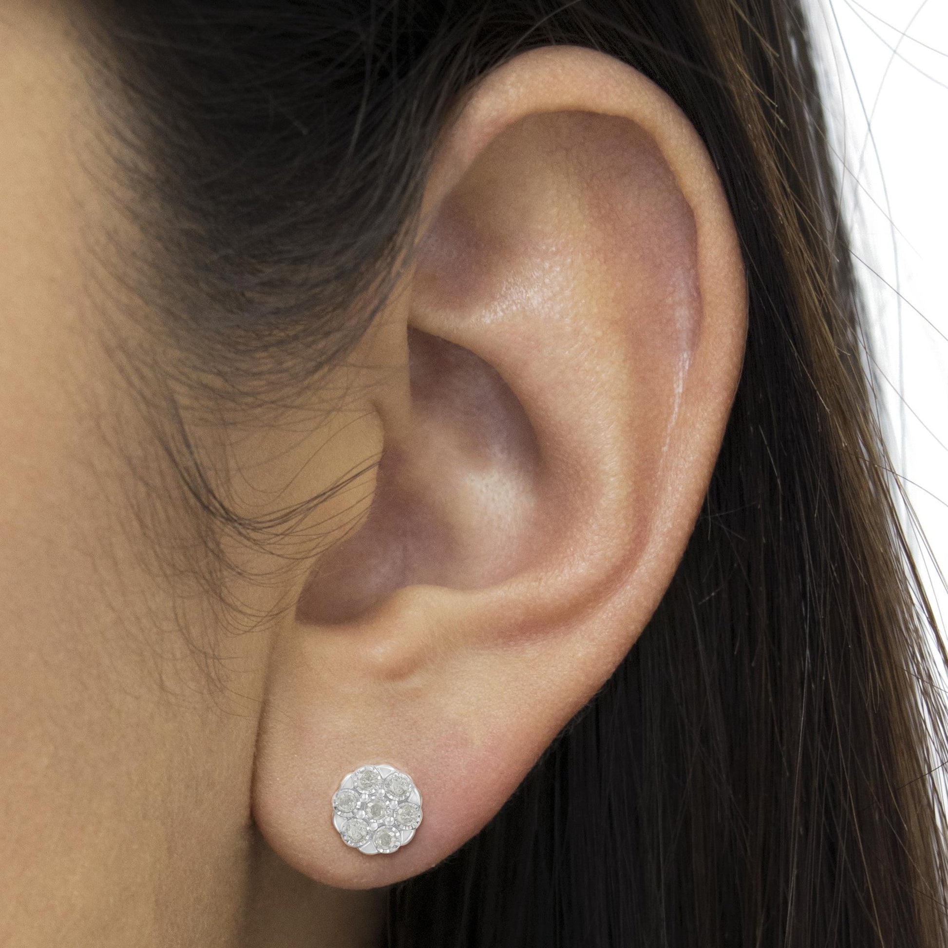 Close-up side view of a white round-shaped earring with multiple white gemstones in a miracle setting worn on an ear.