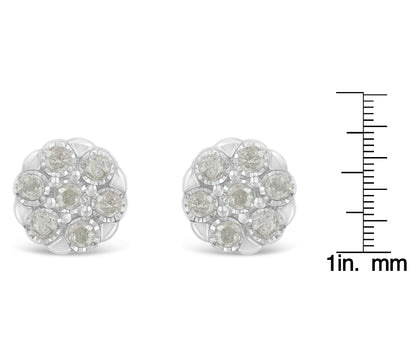 Front-facing close-up of white metal round cluster earrings with multiple white gemstones in a miracle setting, shown beside a size scale.