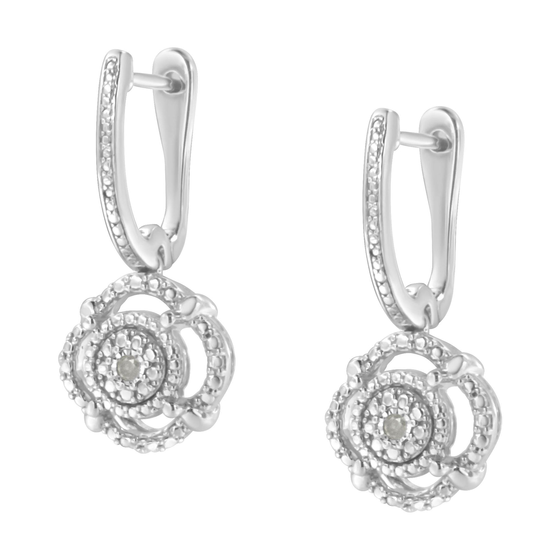 Front-facing shot of a pair of white metal earrings featuring a hoop with small white gemstones set along its length and a circular pendant adorned with round white gemstones in a miracle setting.