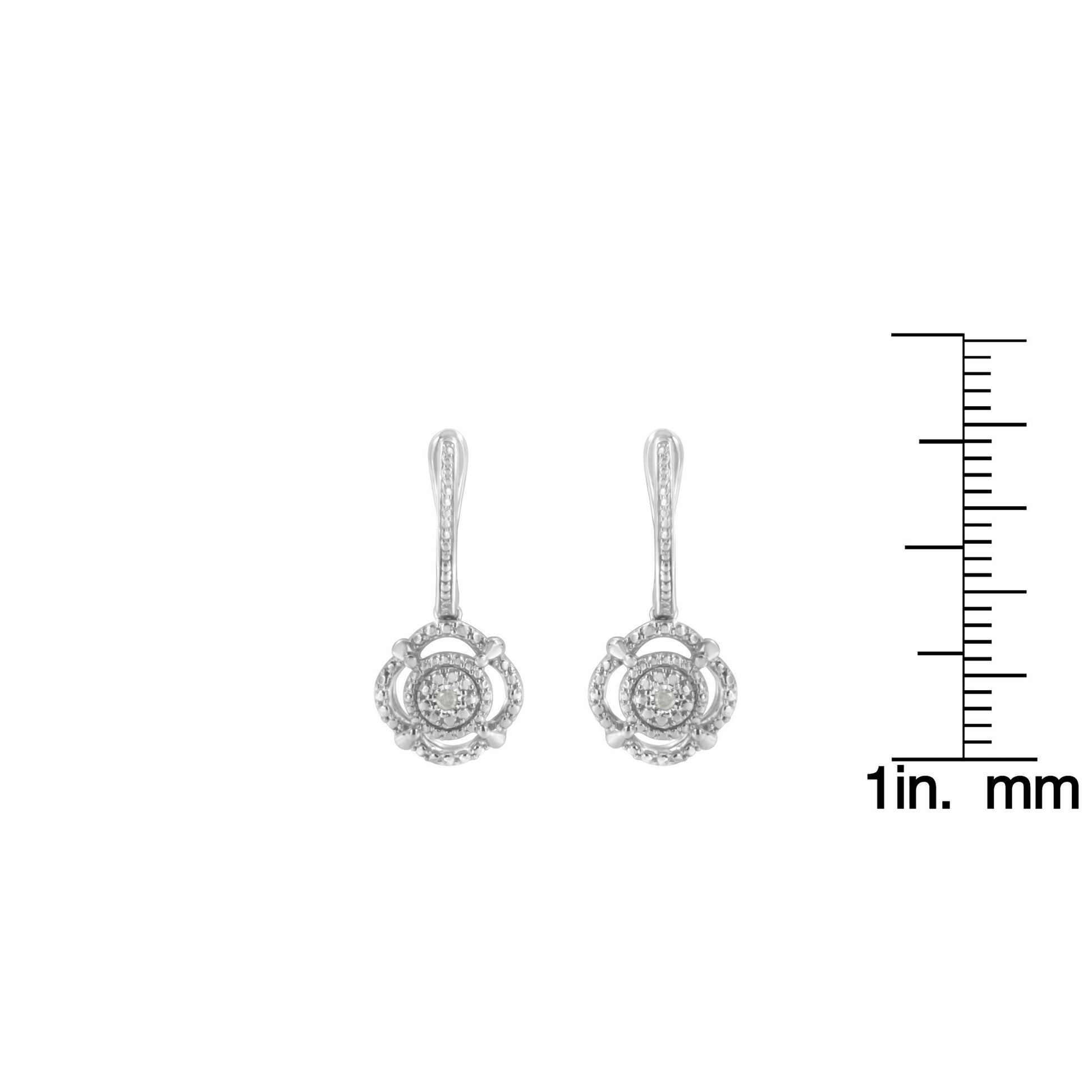 Front view of white metal dangle earrings with round white gemstones, shown next to a ruler for size reference.