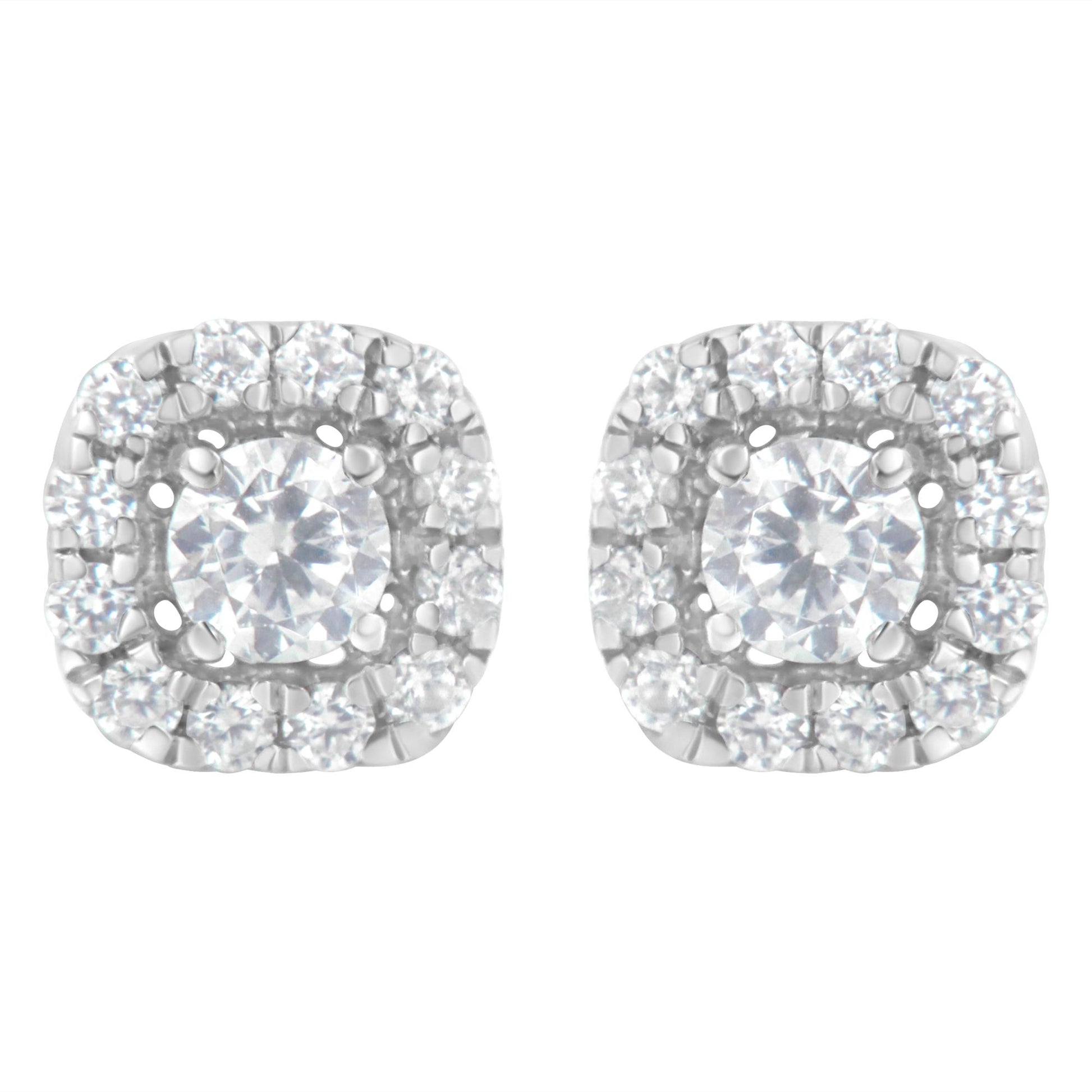 Pair of white metal stud earrings with a central round white gemstone in four-prong settings, surrounded by a halo of smaller round white gemstones in a pave setting, shown from a front angle.
