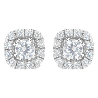 Pair of white metal stud earrings with a central round white gemstone in four-prong settings, surrounded by a halo of smaller round white gemstones in a pave setting, shown from a front angle.