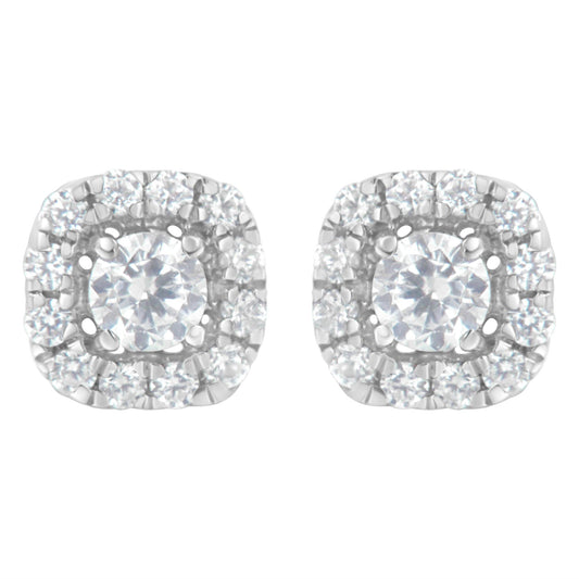 Pair of white metal stud earrings with a central round white gemstone in four-prong settings, surrounded by a halo of smaller round white gemstones in a pave setting, shown from a front angle.