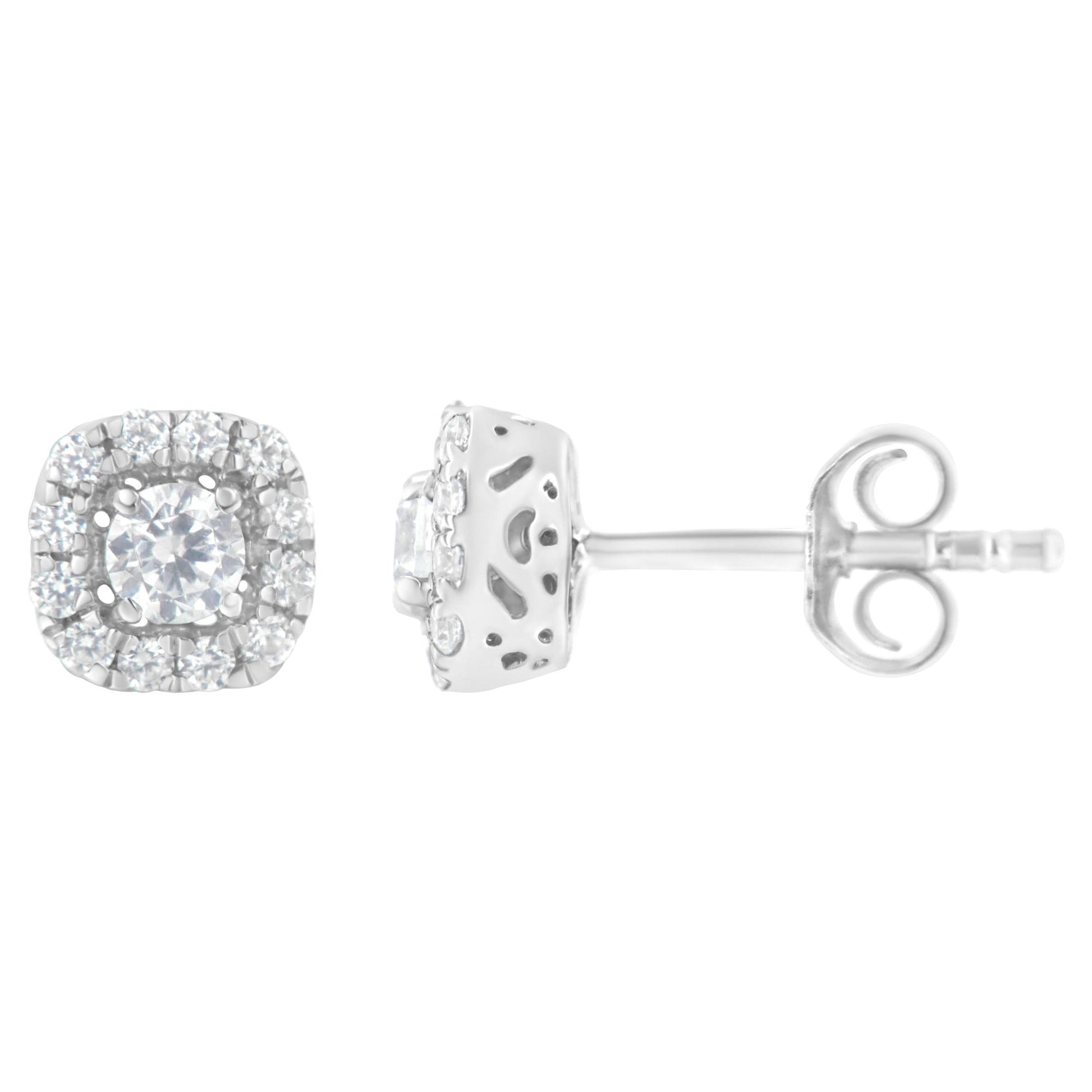 Front and side views of a pair of white metal earrings with a central round white gemstone in a 4-prong setting, surrounded by a halo of smaller round white gemstones in a pave setting.