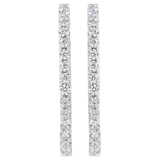 Front-facing shot of a pair of white metal earrings each set with a vertical line of round white gemstones in prong settings.