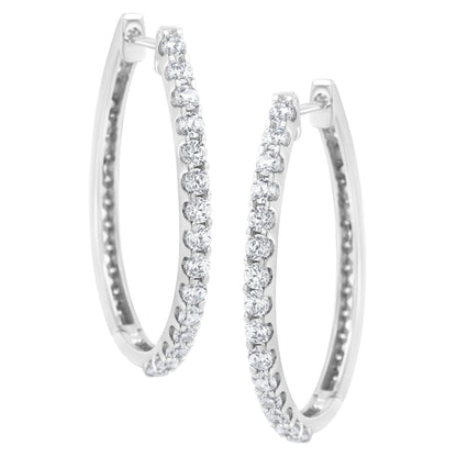 Front angled view of white metal hoop earrings set with round white gemstones in prong settings along the outer edge.