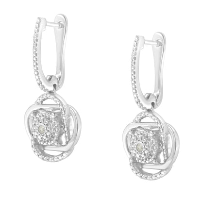 Front angled view of a pair of white metal drop earrings with round white gemstones in a miracle setting.
