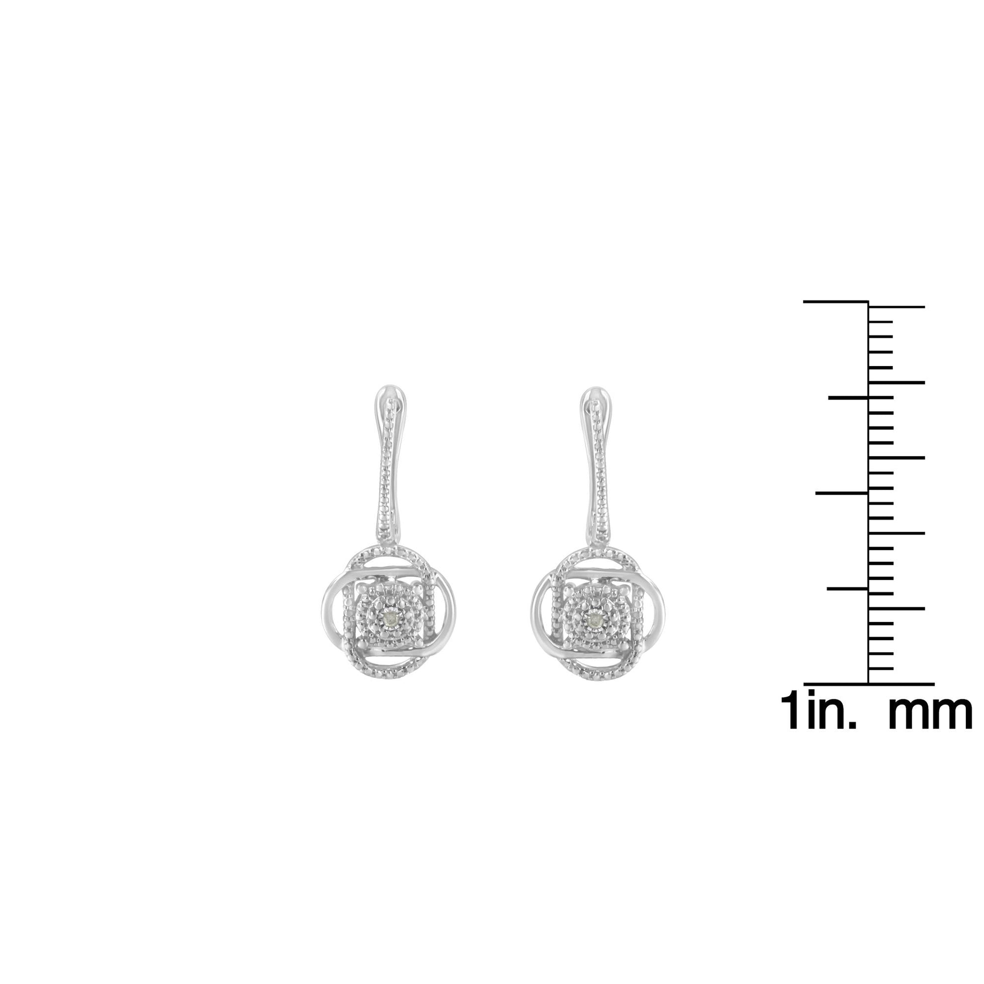 Front view of a pair of white metal earrings with round white gemstones in miracle settings, shown next to a ruler for size reference.