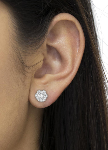 Close-up side view of a white metal earring worn on a model’s ear featuring round white gemstones with invisible and miracle settings and baguette white gemstones with channel settings.