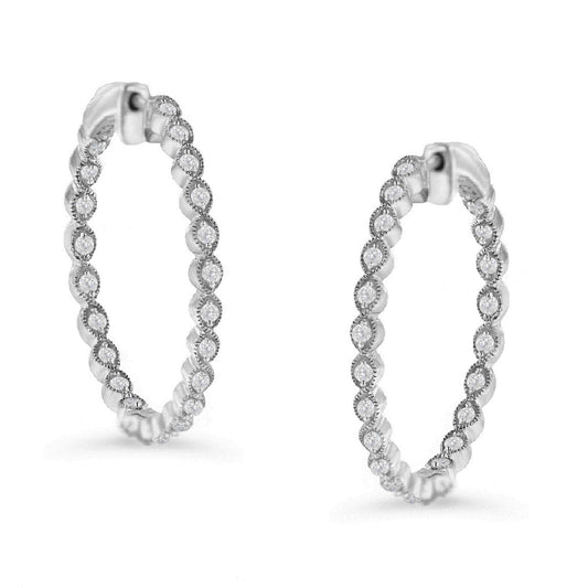 Pair of white metal hoop earrings with round white gemstones in prong settings, shown in a side angle view.