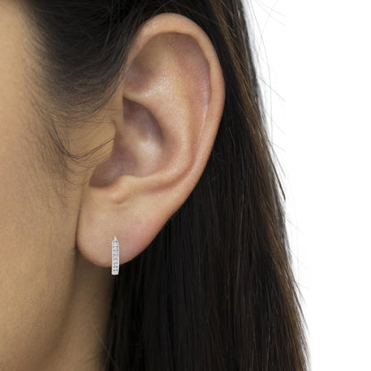 Close-up side view of a white metal earring with a vertical row of round white gemstones in miracle setting, worn on a model's ear.