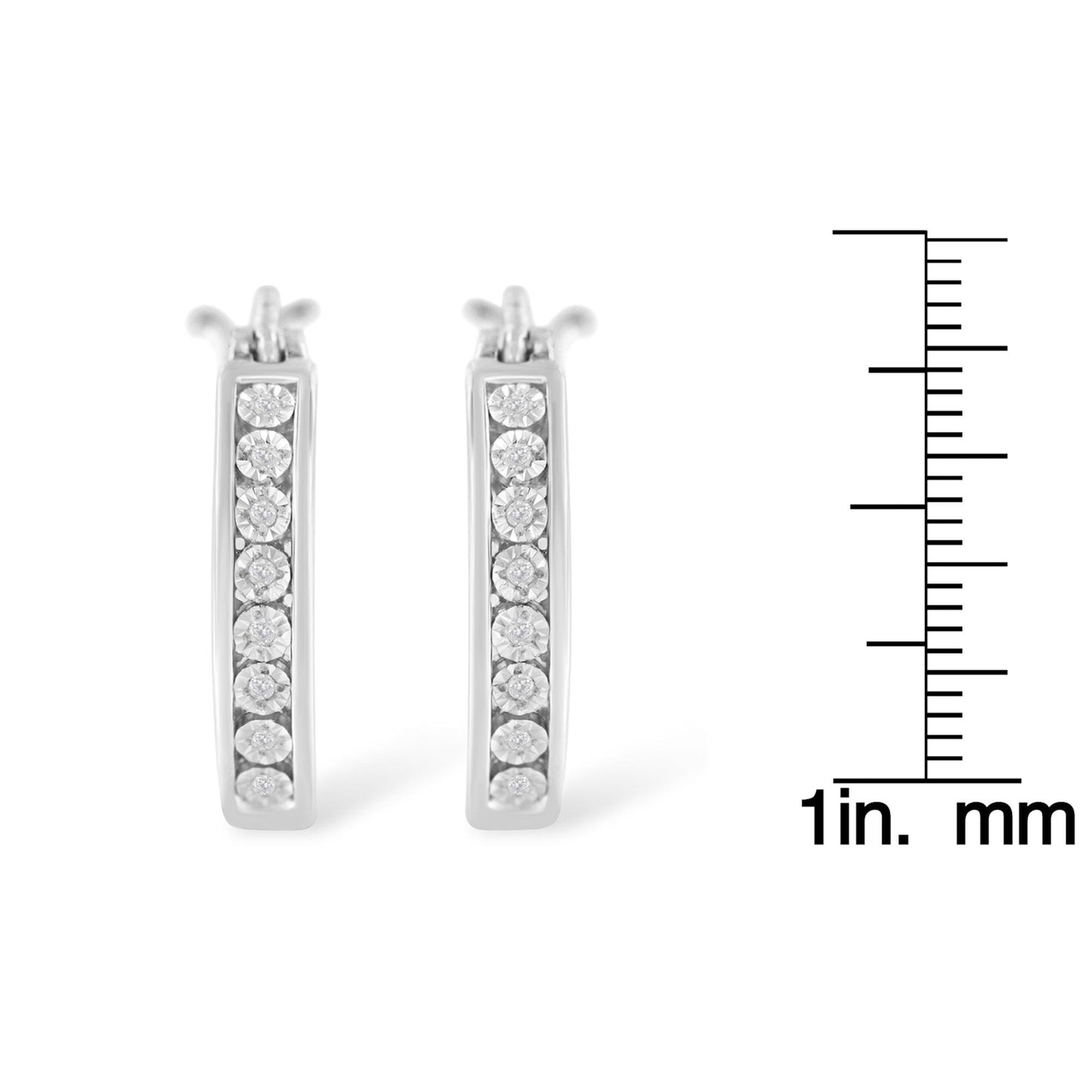 Front view of pair of white metal earrings with white round gemstones set in a vertical line, displayed next to a ruler for size reference.